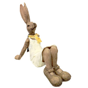 Brown ceramic bunny figurine wearing a white dress with yellow scarf, lying back and looking up, adding whimsy to your decor.