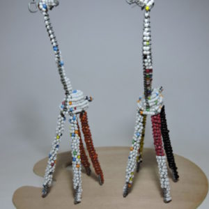 Bead and wire sculpture of a white giraffe with red and black legs and blue beads on its neck.